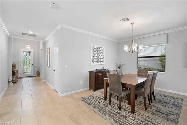 Dining area with ornamental molding, a chandelier, and light tile patterned floors