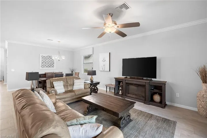 Living area with crown molding, a chandelier, and ceiling fan