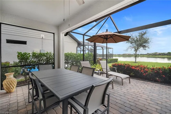 View of patio featuring a sunroom, a water view, a lanai, outdoor dining area, and ceiling fan