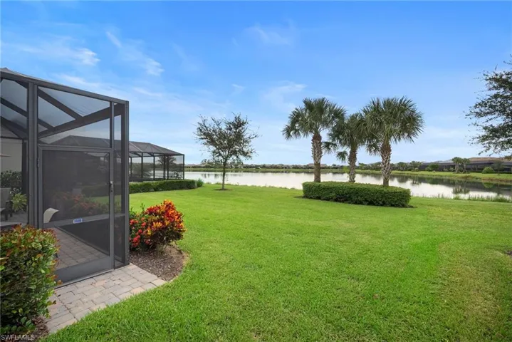 View of grassy yard featuring a water view, a lanai, and a sunroom