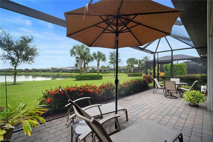 View of patio featuring a sunroom, a water view, glass enclosure, and outdoor dining area