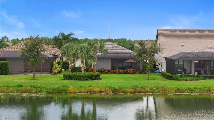 Back of house featuring a water view, a lanai, a lawn, a sunroom, and stucco siding