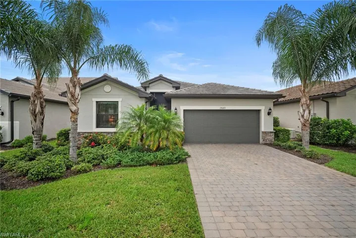 Single story home featuring stucco siding, stone siding, decorative driveway, a tiled roof, and a garage