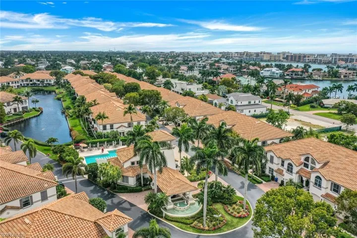 Aerial view of residential area featuring a nearby body of water and a pool area