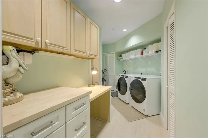 Laundry area with recessed lighting, washer and clothes dryer, light wood finished floors, and cabinet space
