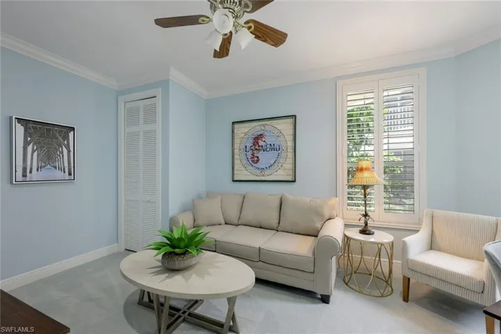 Living room with carpet flooring, crown molding, and a ceiling fan