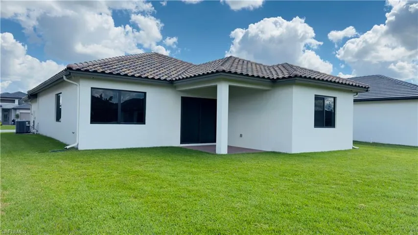 Rear view of property featuring stucco siding, a lawn, and a patio