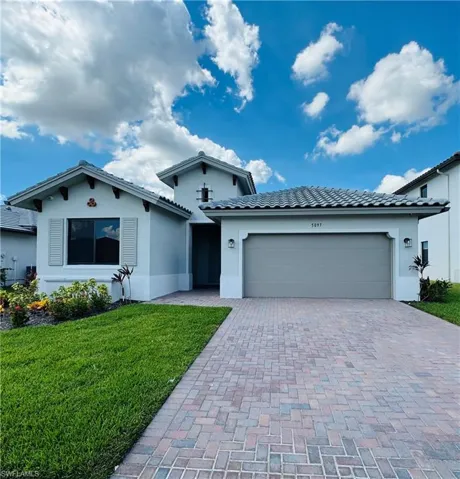 Ranch-style house with stucco siding, decorative driveway, a front lawn, and an attached garage