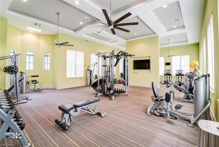 Exercise room with coffered ceiling, ceiling fan, and beamed ceiling
