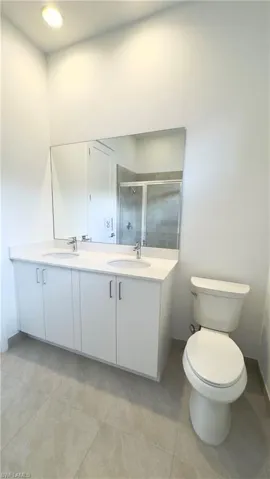 Full bath featuring double vanity, a stall shower, and light tile patterned floors
