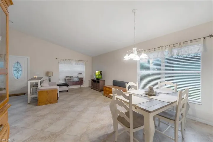 Tiled dining space with lofted ceiling and a notable chandelier