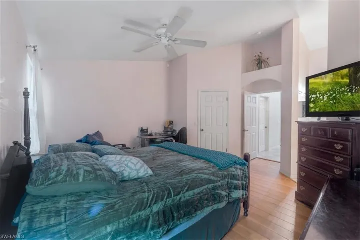 Bedroom featuring light hardwood / wood-style floors, high vaulted ceiling, and ceiling fan