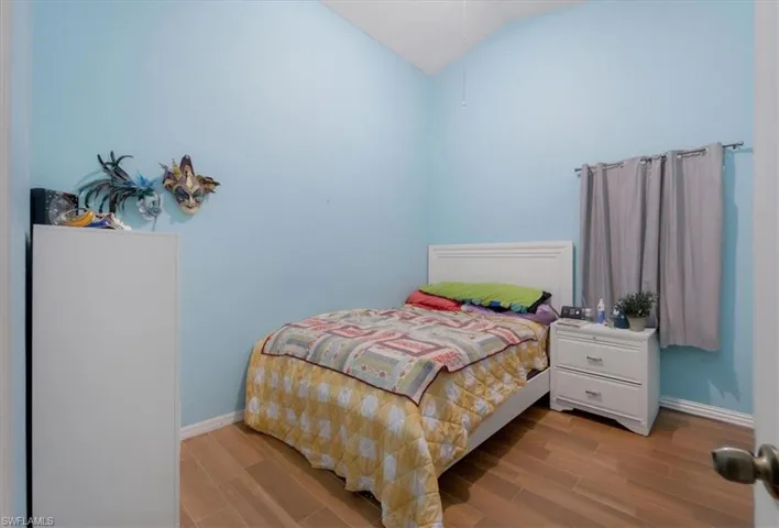 Bedroom with lofted ceiling and light wood-type flooring