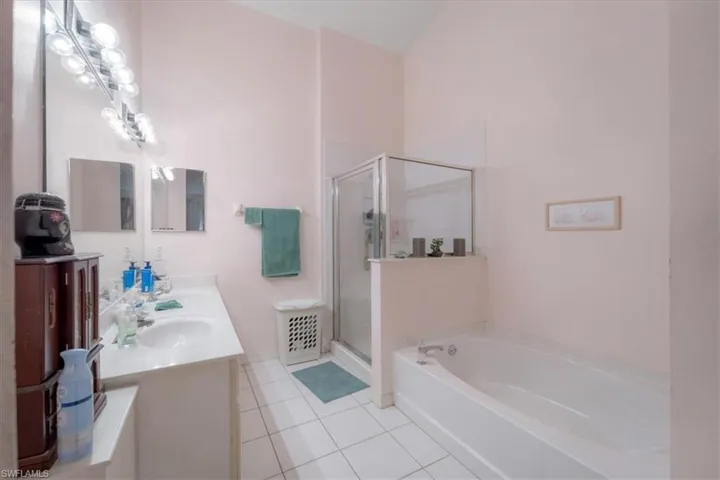 Bathroom featuring shower with separate bathtub, tile patterned flooring, and double sink vanity