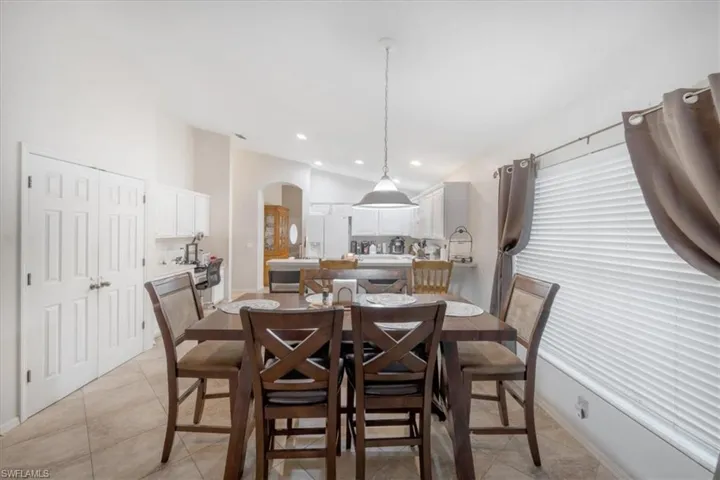 Tiled dining area featuring lofted ceiling