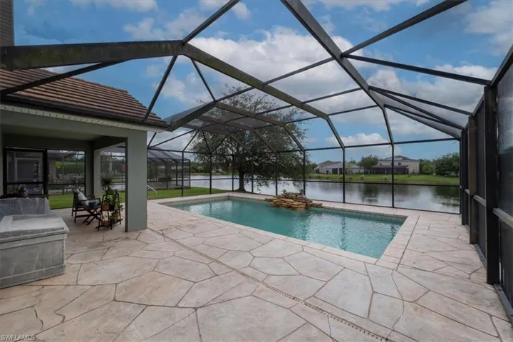 View of pool with a water view, a patio, and glass enclosure