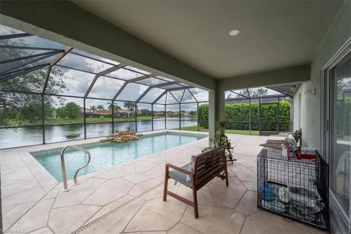 View of pool with glass enclosure and a patio area