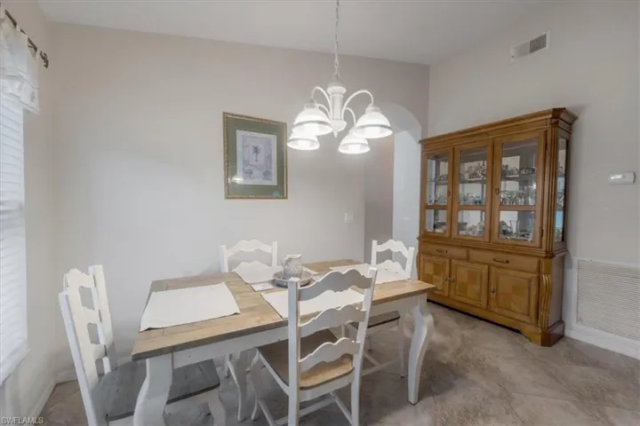 Tiled dining room with a notable chandelier and vaulted ceiling