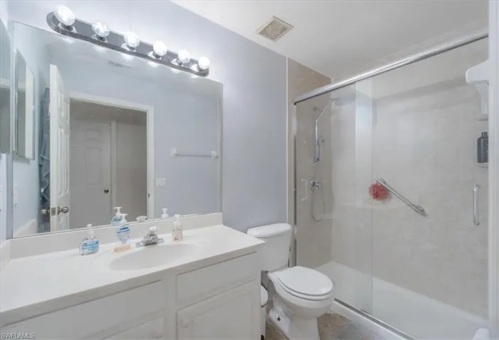 Bathroom with vanity, a shower with shower door, and toilet