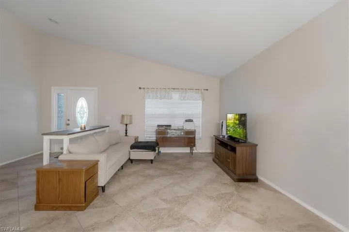 Tiled living room featuring high vaulted ceiling