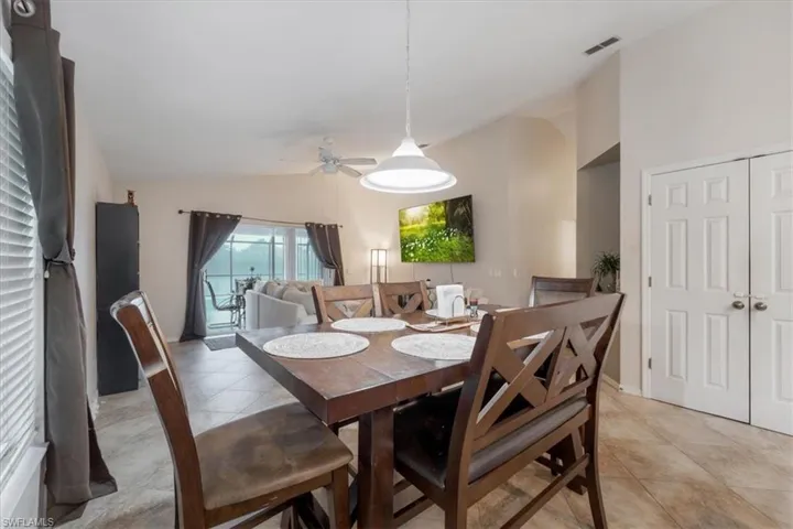 Dining space with light tile patterned floors, vaulted ceiling, and ceiling fan