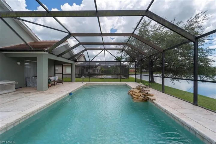 View of pool featuring a lanai, a patio, and a lawn