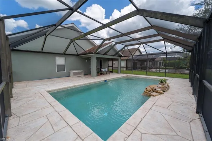 View of pool featuring a patio and glass enclosure