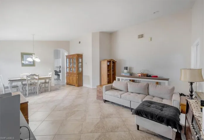 Living room with high vaulted ceiling, a chandelier, and light tile patterned floors