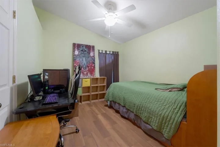 Bedroom with vaulted ceiling, ceiling fan, and light hardwood / wood-style floors