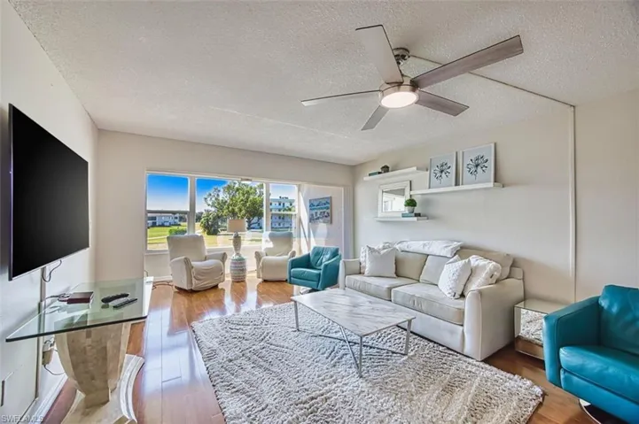 Living area featuring wood finished floors, ceiling fan, and a textured ceiling