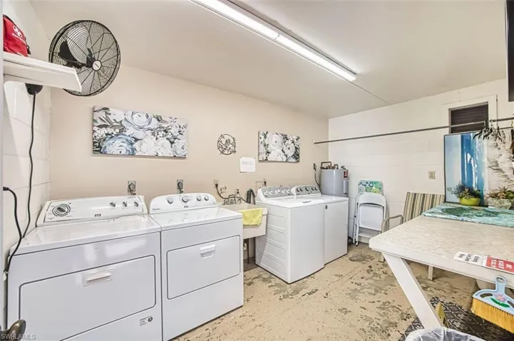 Laundry room with unfinished concrete flooring, independent washer and dryer, and water heater