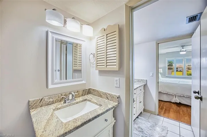 Bathroom with vanity, light tile patterned floors, connected bathroom, a textured ceiling, and ceiling fan