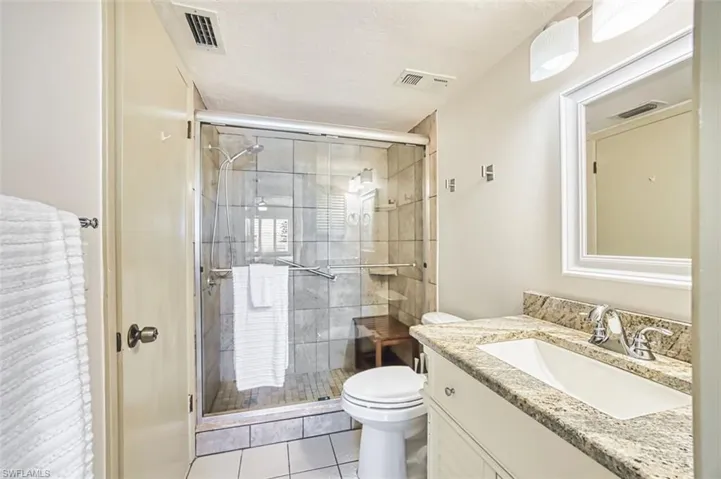 Bathroom featuring vanity, a shower stall, light tile patterned floors, and a textured ceiling