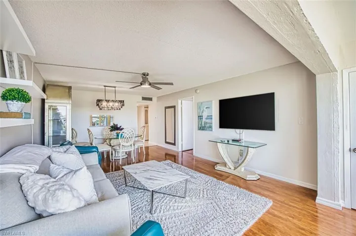 Living room with light wood-style flooring, a textured ceiling, and ceiling fan