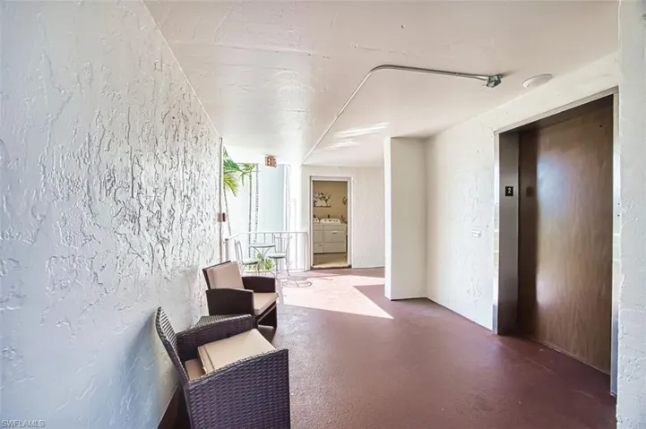 Hallway with a textured wall, elevator, finished concrete flooring, and independent washer and dryer