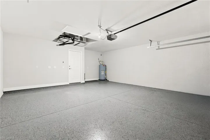 Spacious garage featuring epoxy flooring, a paneled interior door, and a built-in overhead storage rack
