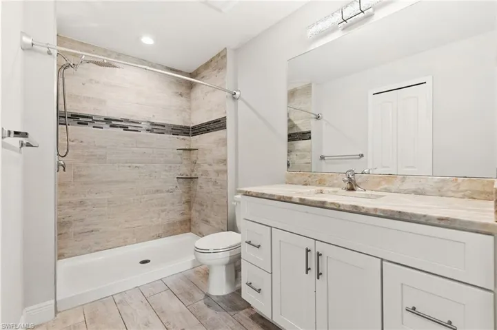 Bathroom featuring a walk-in shower with wood-look tile, decorative accent tile, and two built-in shelves