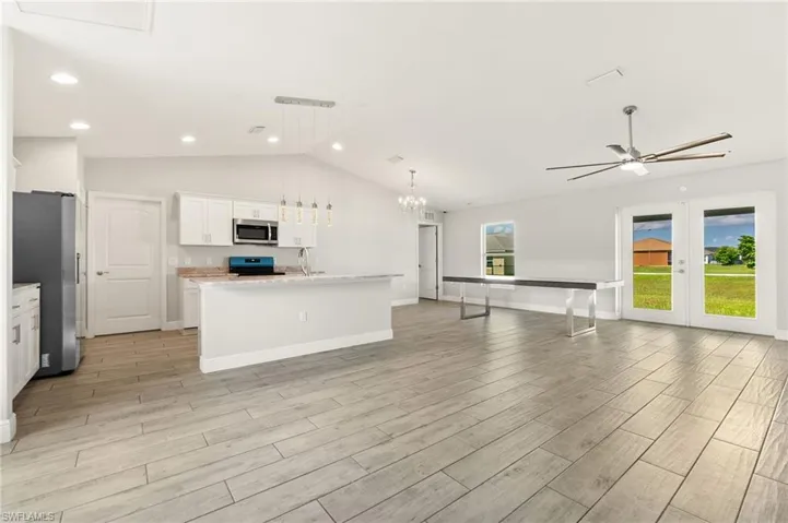 Open-concept interior featuring light wood-look tile flooring, vaulted ceiling, and recessed lighting