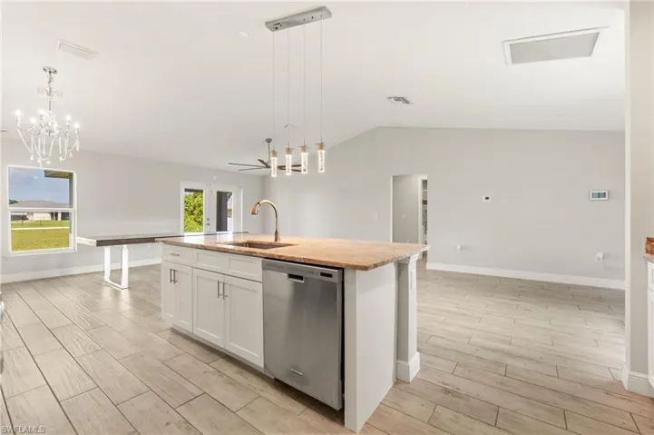 Open-concept living space featuring a central kitchen island with a built-in sink and stainless steel dishwasher
