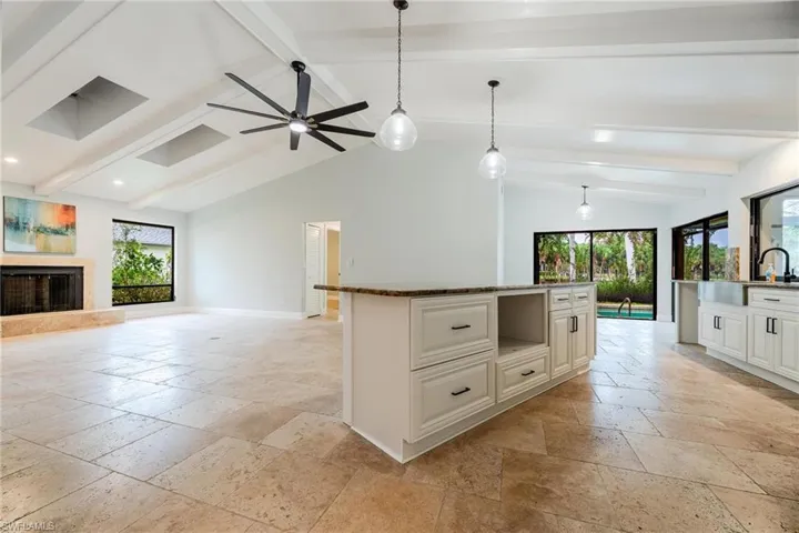 Kitchen with lofted ceiling with beams, hanging light fixtures, ceiling fan, and a center island