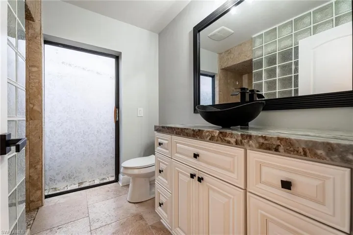 Bathroom with vanity, plenty of natural light, toilet, and a shower