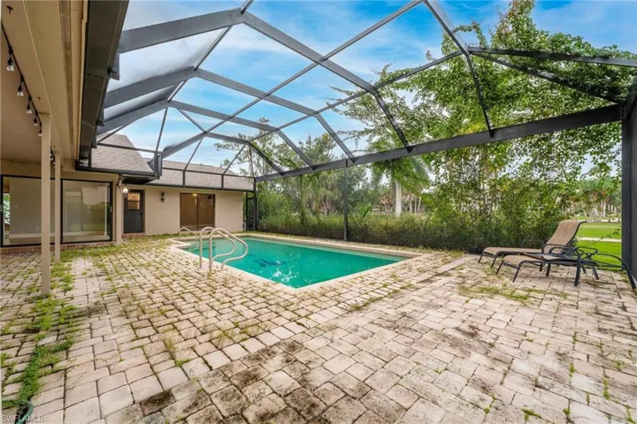 View of pool with glass enclosure and a patio