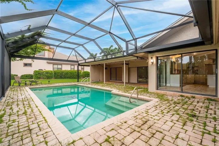 View of swimming pool with glass enclosure, ceiling fan, and a patio area