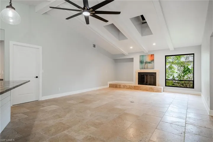 Unfurnished living room with ceiling fan, beamed ceiling, and high vaulted ceiling