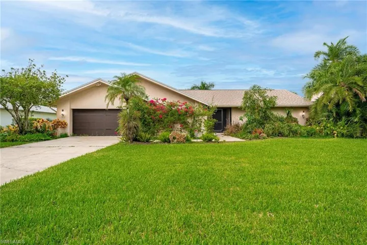 Ranch-style house featuring a garage and a front lawn