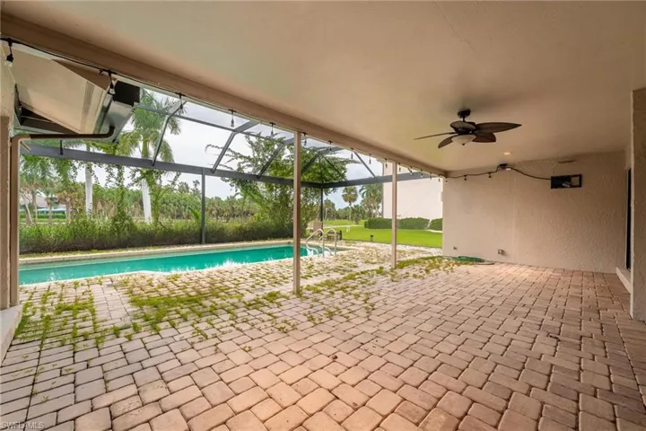 View of swimming pool with glass enclosure, a patio area, and ceiling fan