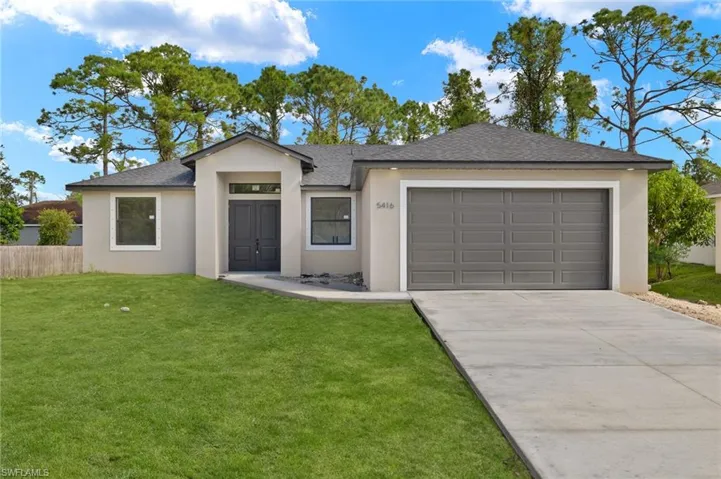 Single story home with a garage and a front lawn