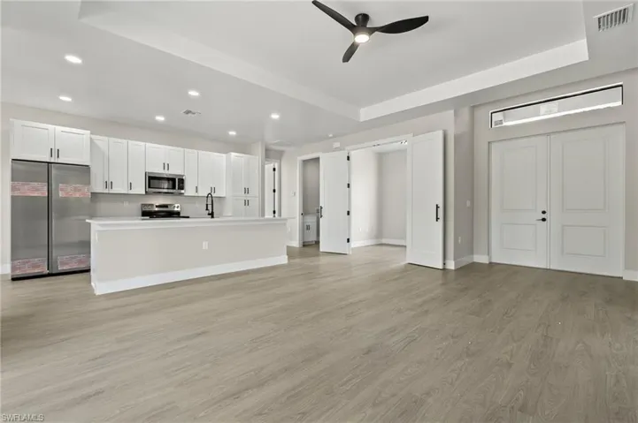 Kitchen featuring light hardwood / wood-style flooring, ceiling fan, appliances with stainless steel finishes, and white cabinetry