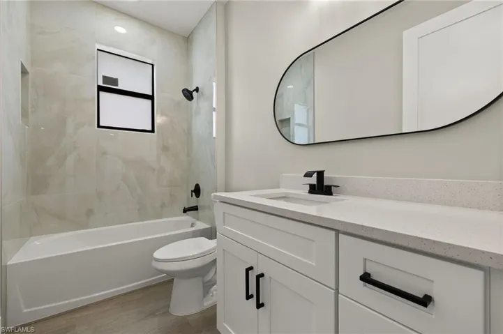 Full bathroom featuring tiled shower / bath, vanity, toilet, and hardwood / wood-style floors
