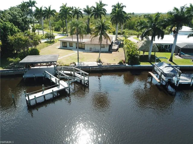 Dock featuring boat lift, a water view, and a yard